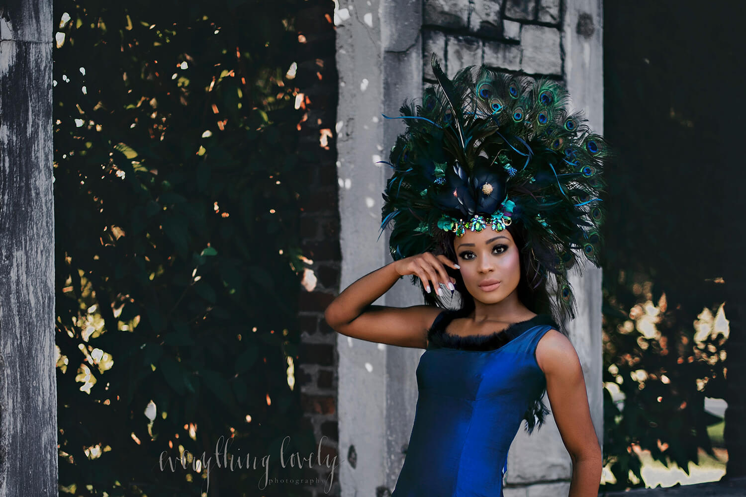 <alt>beautiful girl model wearing handmade peacock headpiece by honeydrops designs posing in park</alt>