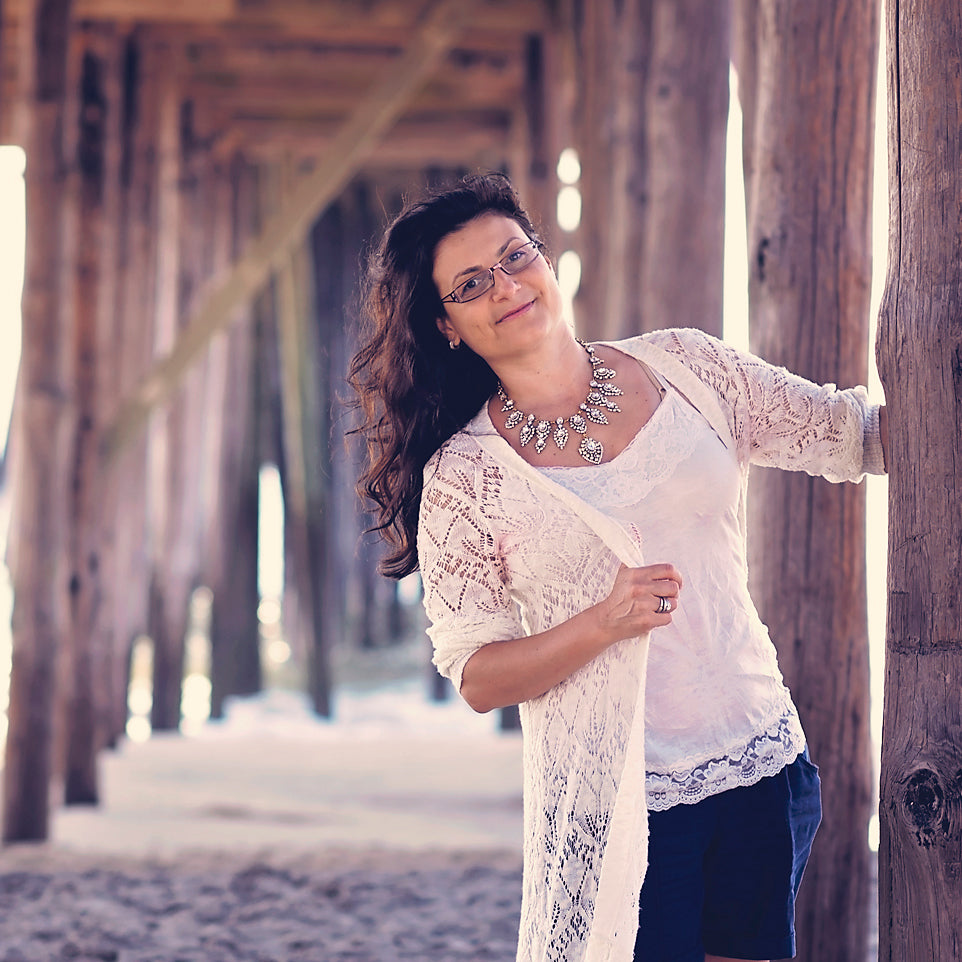 Honeydrops Designs founder and head designer Daniela Mallas posing by the pier in white sweater and sparkly necklace