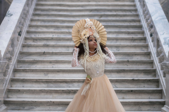 <alt>Beautiful young girl wearing cream and gold flower headdress and a princess dress posing in front of marble steps</alt>