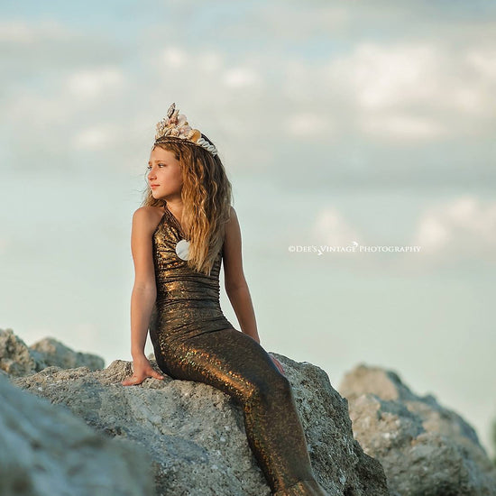 little mermaid sitting on a rock by the ocean wearing couture handmade seashell crown by honeydrops designs